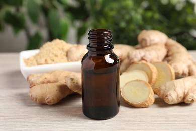 Photo of Ginger essential oil in bottle on light wooden table