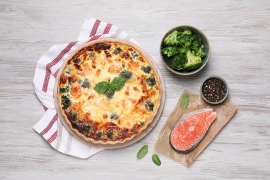 Delicious homemade quiche and ingredients on wooden table, flat lay