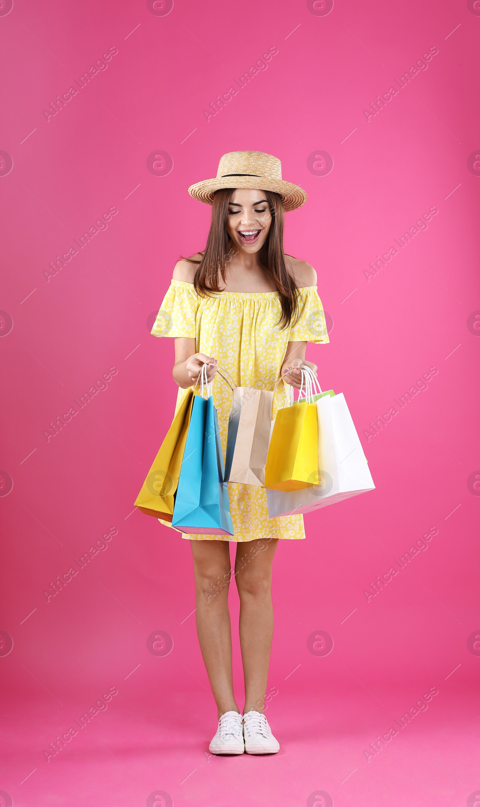 Photo of Young woman with shopping bags on color background