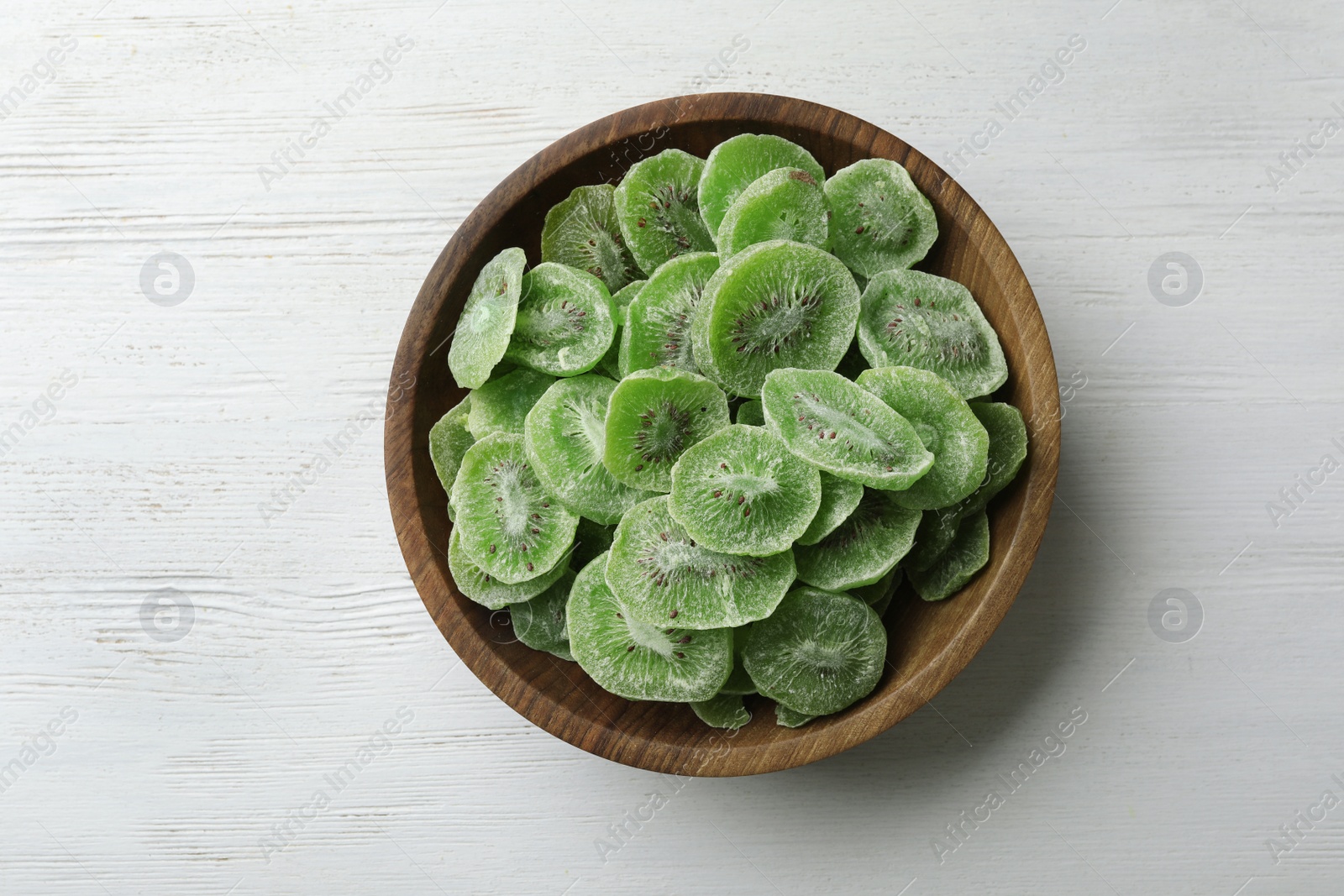 Photo of Bowl with slices of kiwi on wooden background, top view. Dried fruit as healthy food