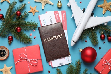 Photo of Flat lay composition with Christmas decorations, passport and airline tickets on blue background. Winter vacation
