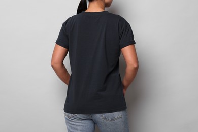 Photo of Woman wearing black t-shirt on light grey background, closeup