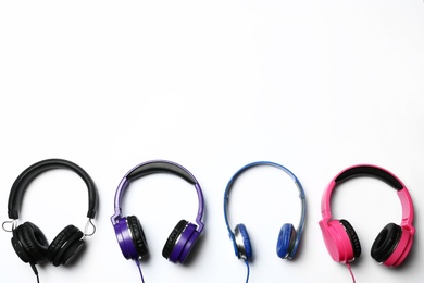 Many stylish headphones on white background, top view