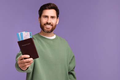 Smiling man showing passport and tickets on purple background. Space for text