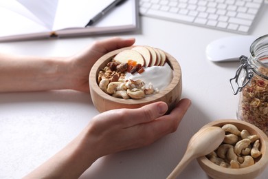 Woman with tasty granola at workplace, closeup