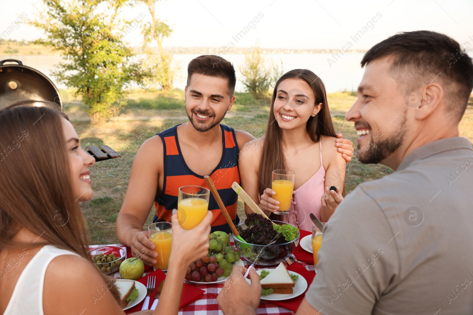 Photo of Happy young people having picnic at table in park