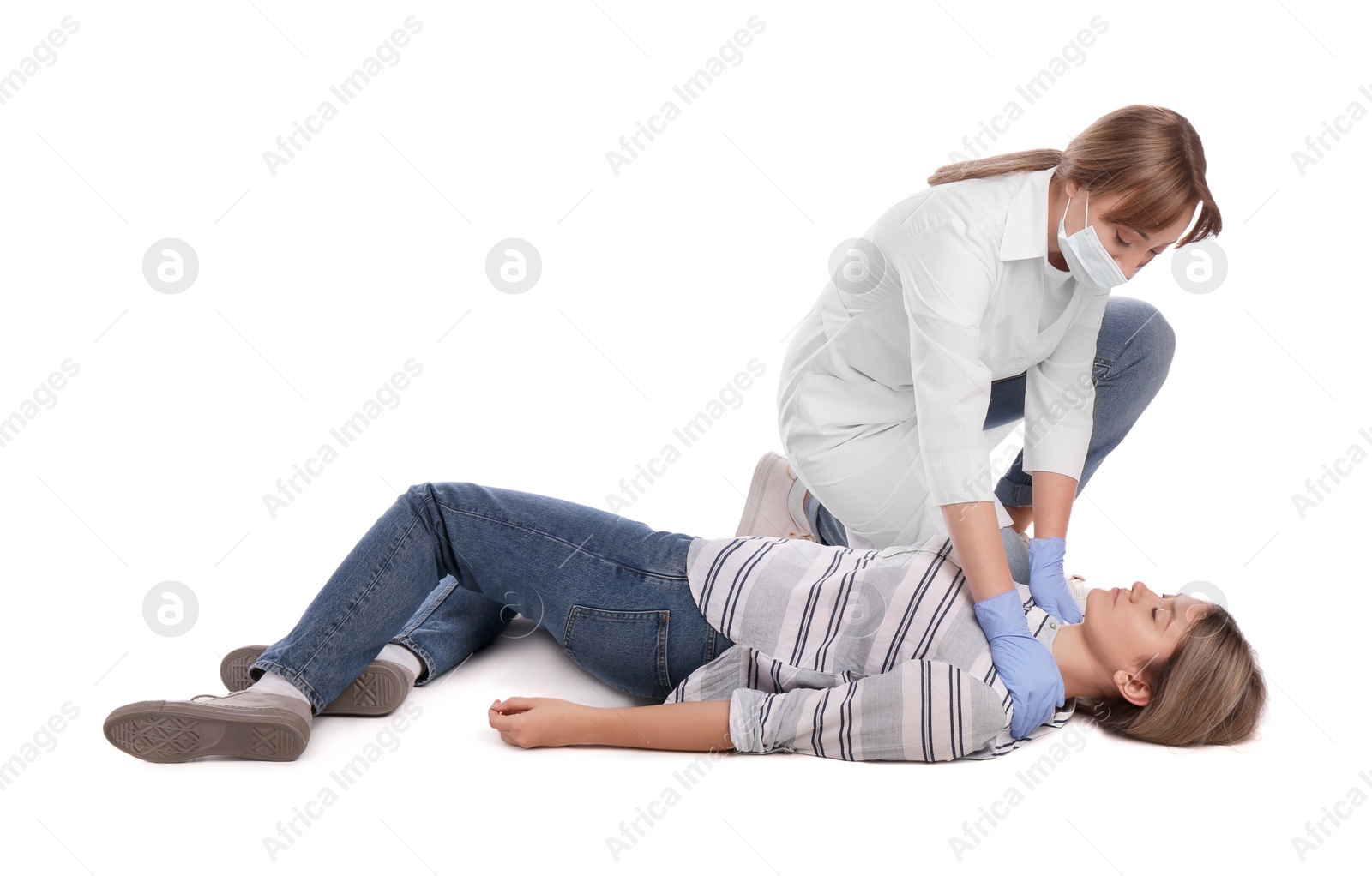 Photo of Doctor in uniform and protective mask performing first aid on unconscious woman against white background