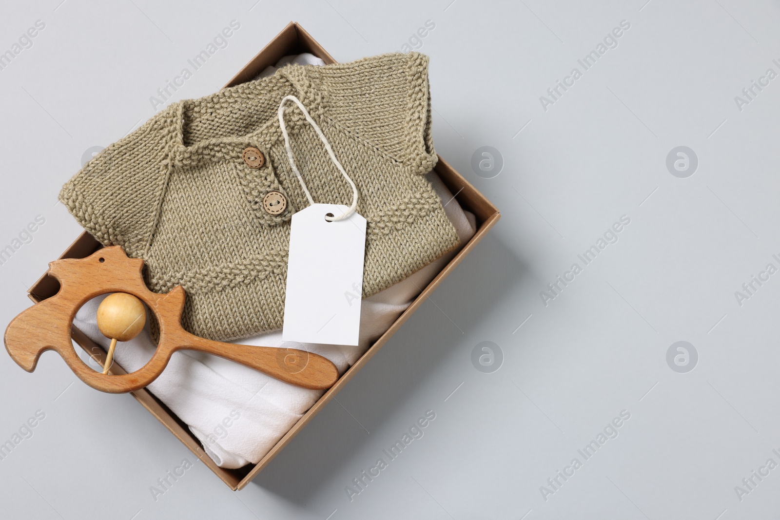 Photo of Different baby accessories, clothes and blank card in box on light grey background, top view. Space for text