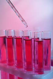 Photo of Dripping reagent into test tube with red liquid, closeup. Laboratory analysis