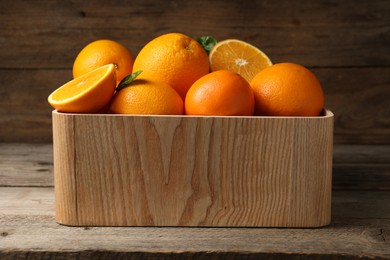 Many whole and cut ripe oranges on wooden table