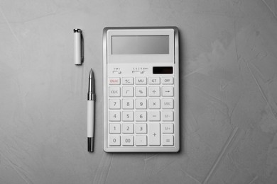 Photo of Calculator and pen on grey table, top view