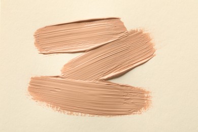 Photo of Sample of liquid skin foundation on beige background, top view