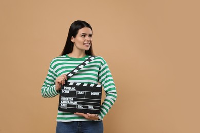 Photo of Happy actress with clapperboard on beige background, space for text. Film industry