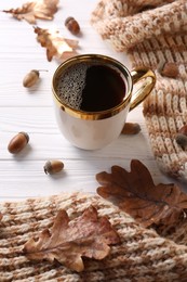 Cup of hot drink, spices, leaves and knitted scarf on white wooden table. Cozy autumn atmosphere