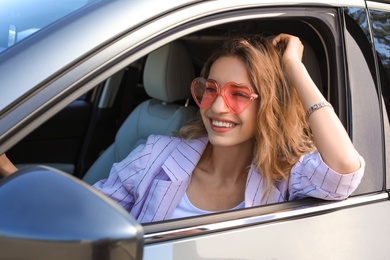 Photo of Happy woman with heart shaped glasses in car