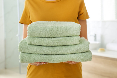 Woman holding fresh towels in bathroom, closeup