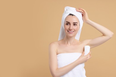 Beautiful woman applying deodorant on beige background, space for text