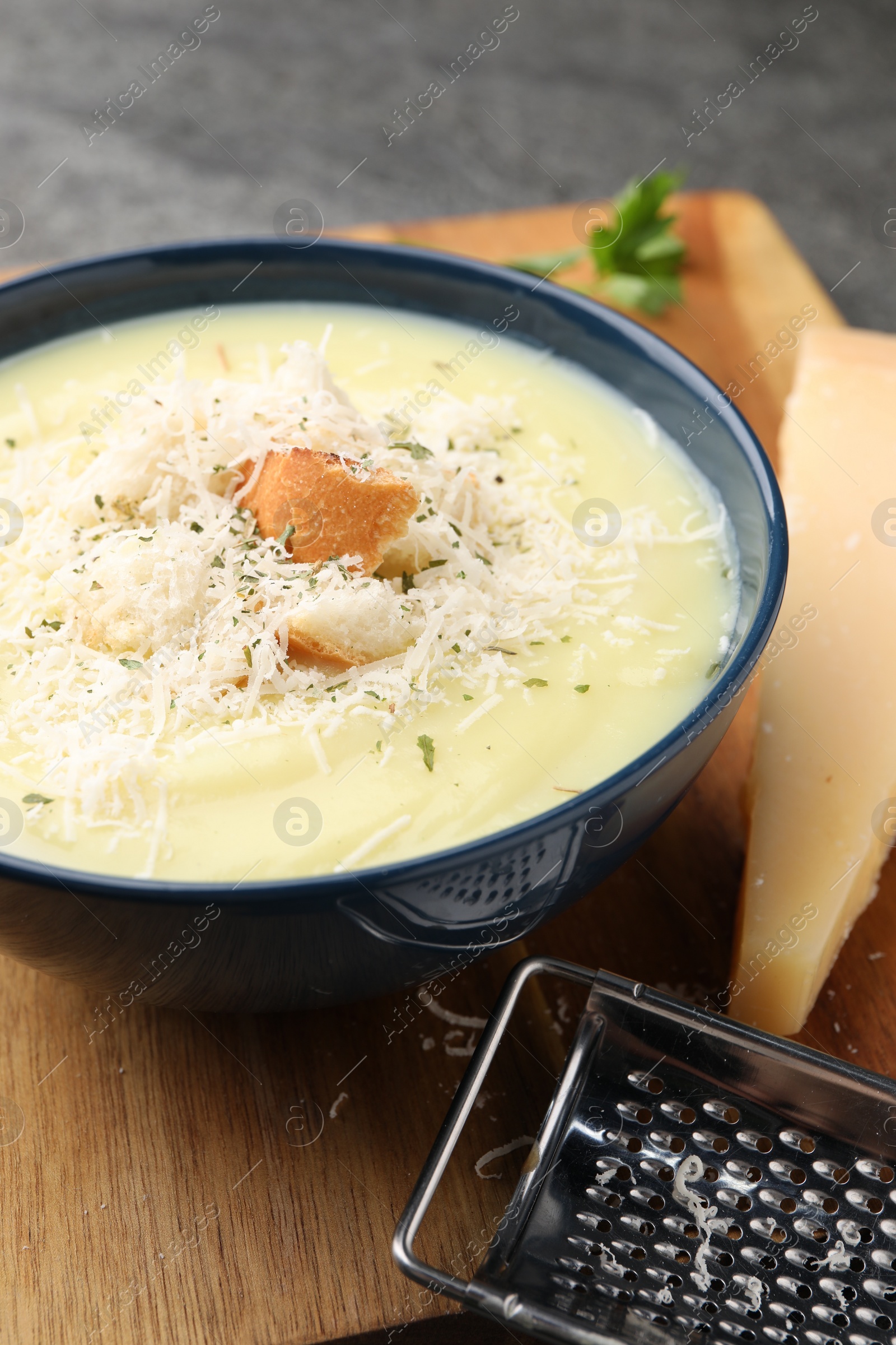 Photo of Delicious cream soup with parmesan cheese and croutons in bowl on table