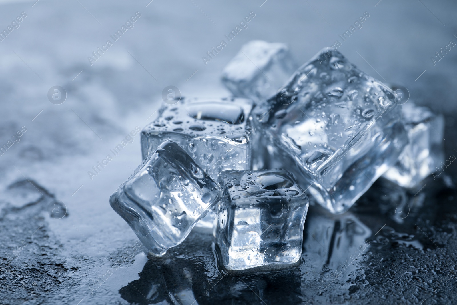 Photo of Crystal clear ice cubes with water drops on grey table, closeup