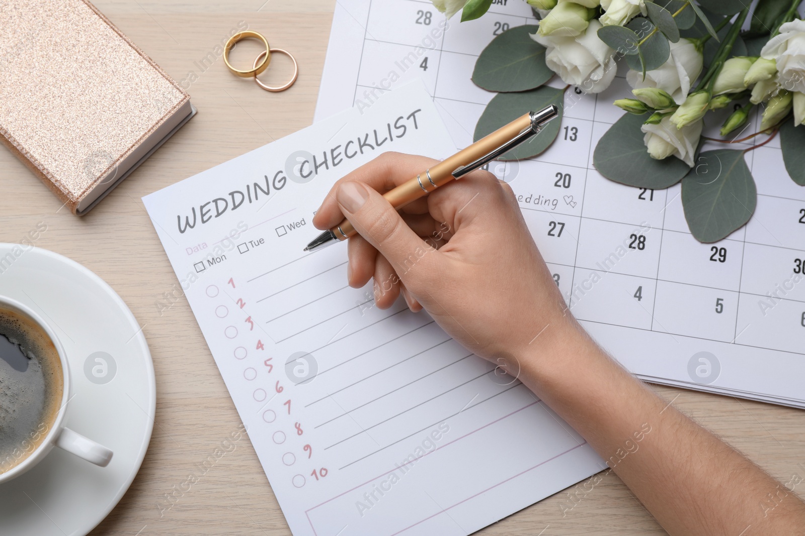 Photo of Woman filling Wedding Checklist at wooden table, top view