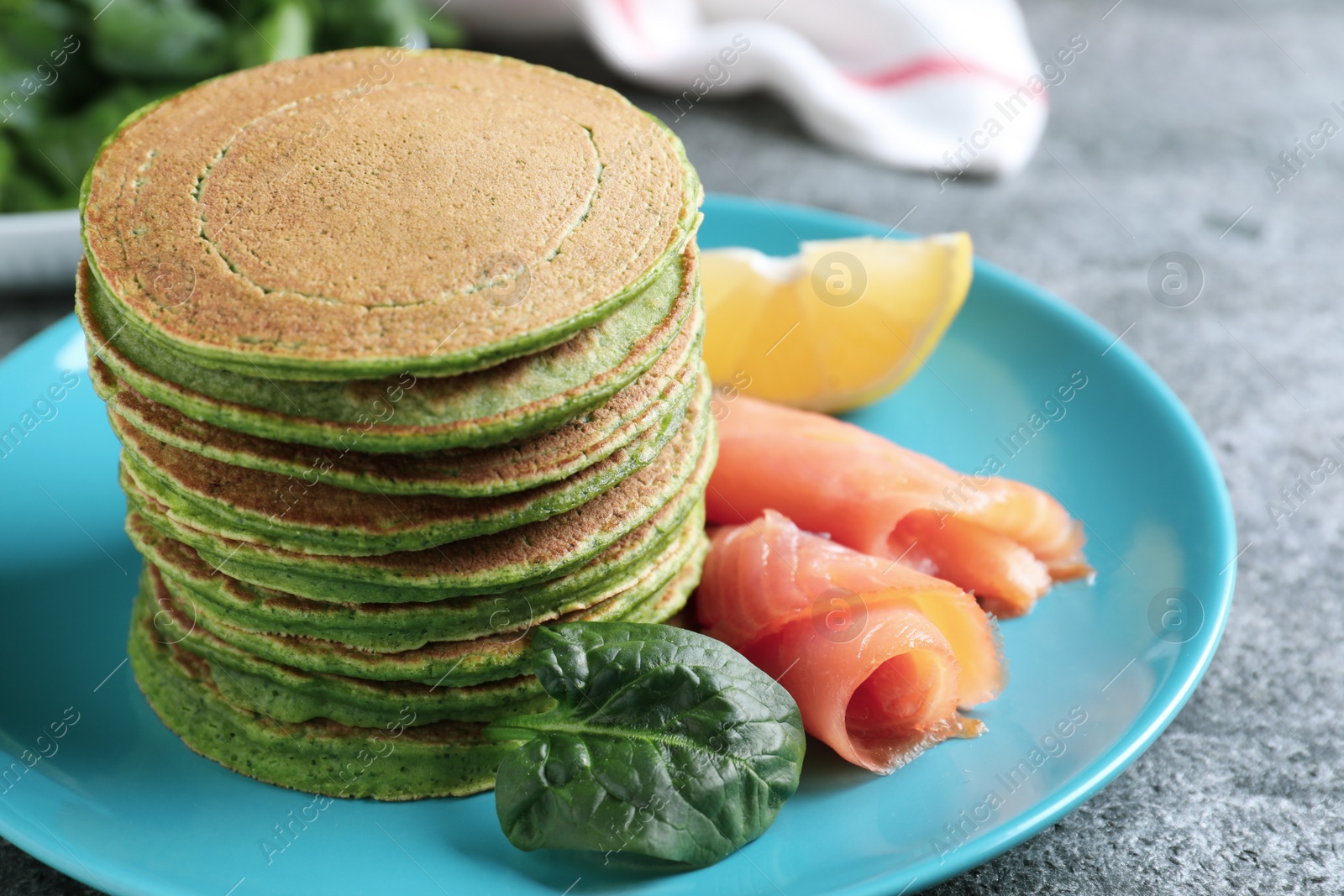 Photo of Tasty spinach pancakes with salmon on grey table, closeup