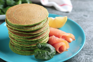 Tasty spinach pancakes with salmon on grey table, closeup