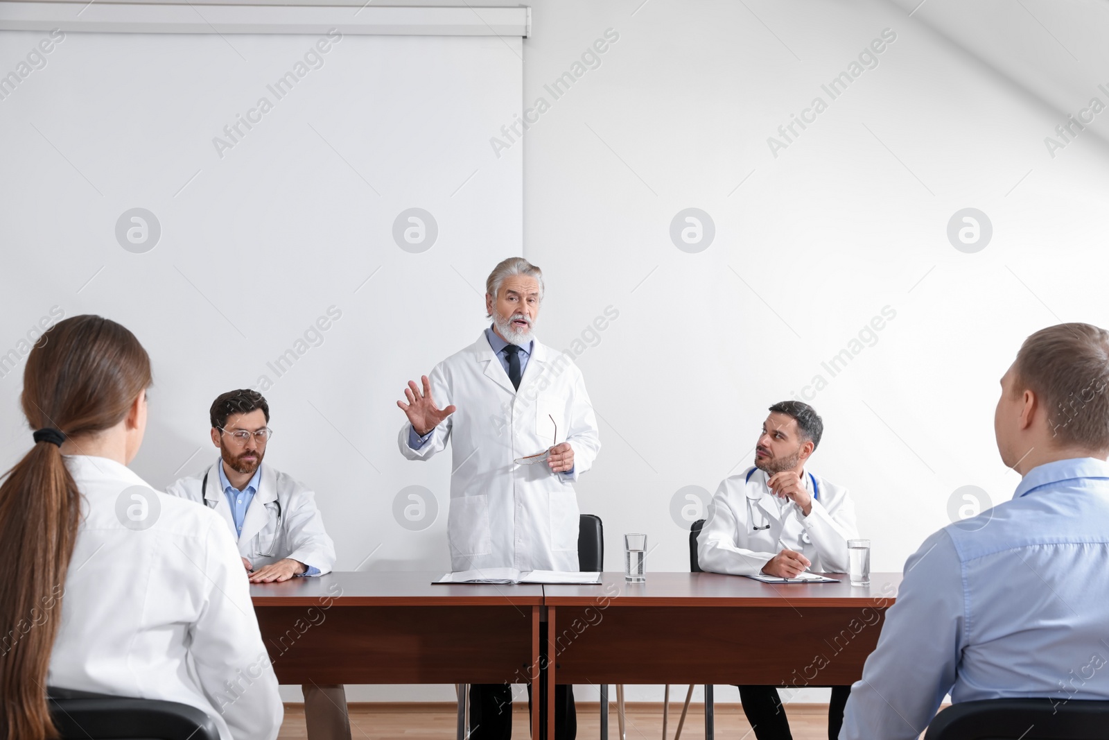 Photo of Senior doctor having discussion with audience during medical conference in meeting room
