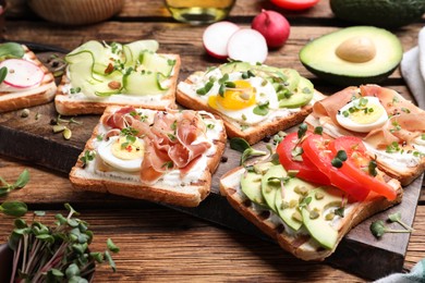 Different delicious sandwiches with microgreens on wooden board