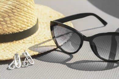 Photo of Stylish hat, sunglasses and jewelry on grey surface, closeup