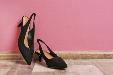 Photo of Pair of female shoes on floor against color wall