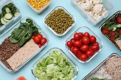 Different containers with fresh products on light blue background, flat lay