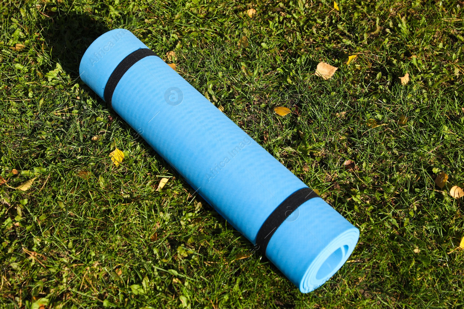 Photo of Blue karemat or fitness mat on fresh green grass outdoors, above view