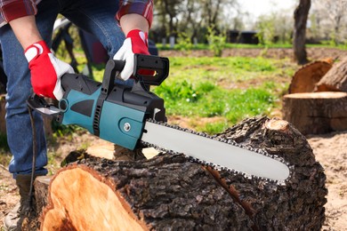 Photo of Man sawing wooden log on sunny day, closeup