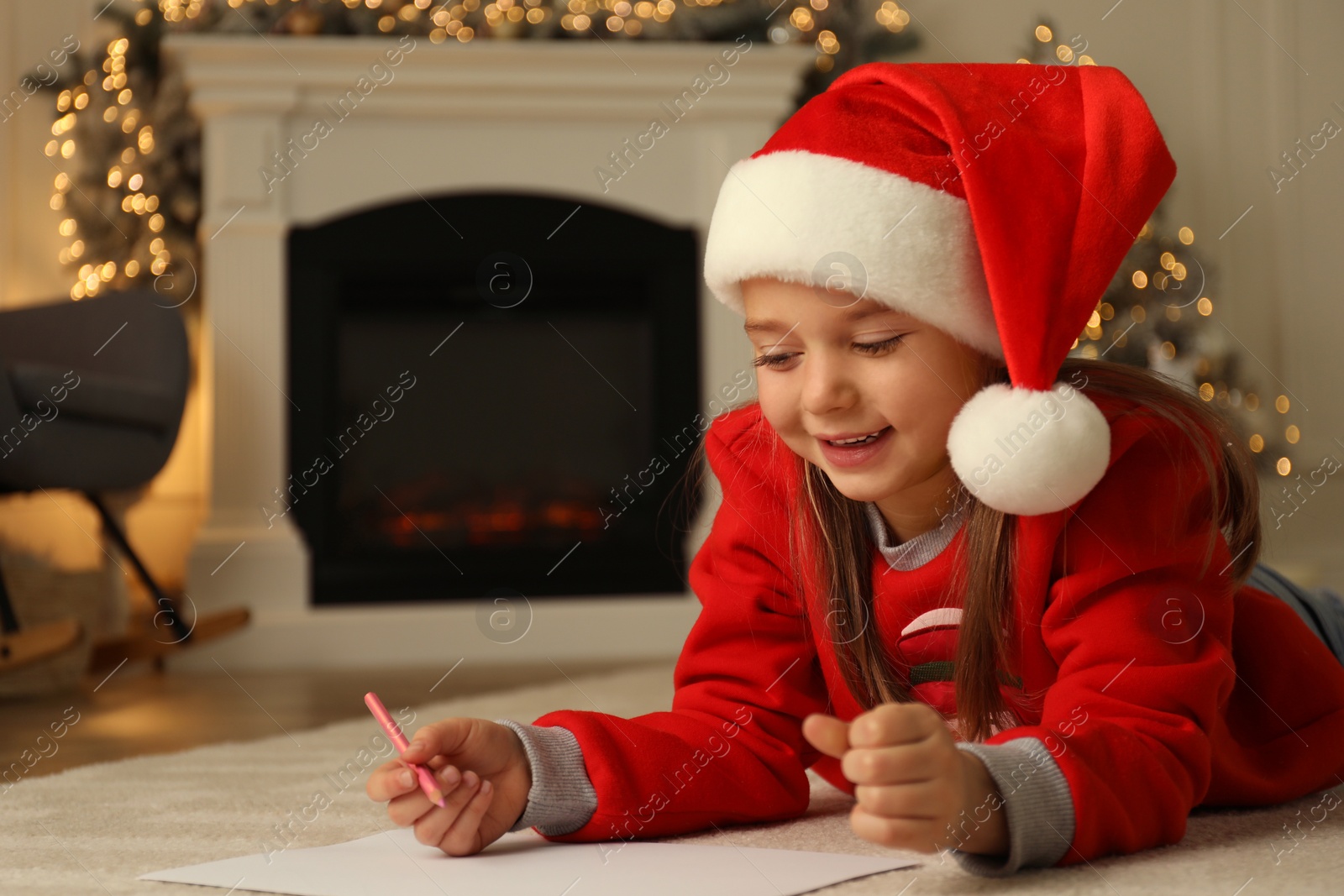 Photo of Cute child writing letter to Santa Claus while lying on floor at home, space for text. Christmas celebration