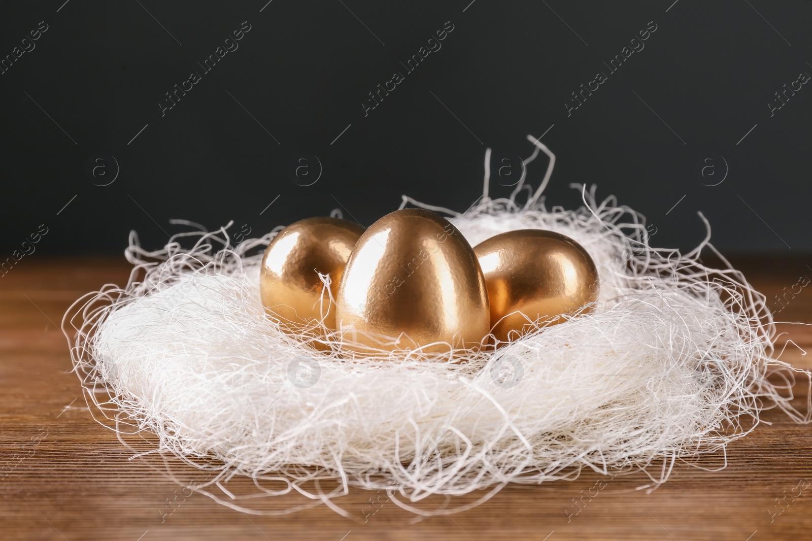 Photo of Golden eggs in nest on wooden table. Pension planning