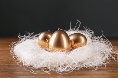 Golden eggs in nest on wooden table. Pension planning