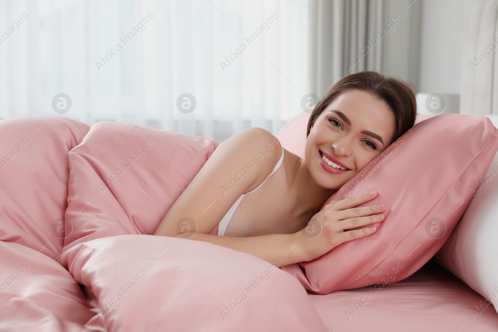 Photo of Young woman lying in comfortable bed with silky linens