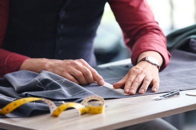 Tailor working at table in atelier, closeup