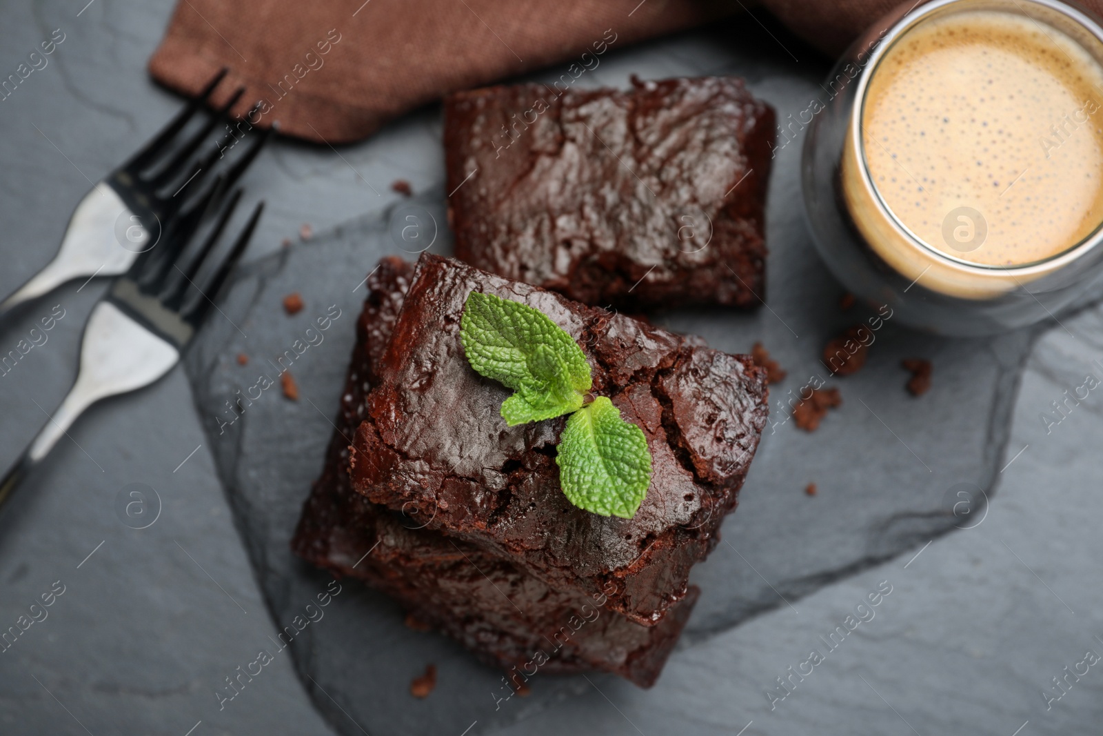 Photo of Delicious chocolate brownie with fresh mint served on black table, flat lay