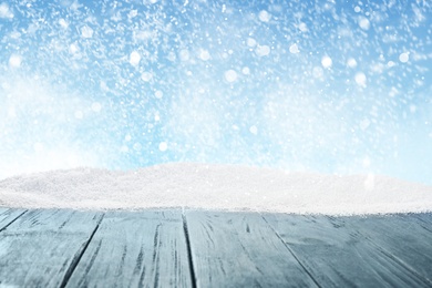 Image of Wooden surface with snow against blue background, bokeh effect