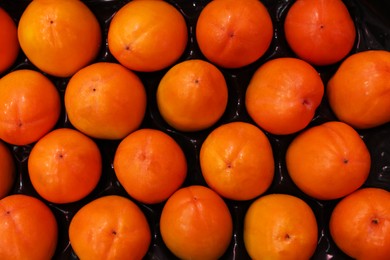 Many fresh persimmons in container at market, top view