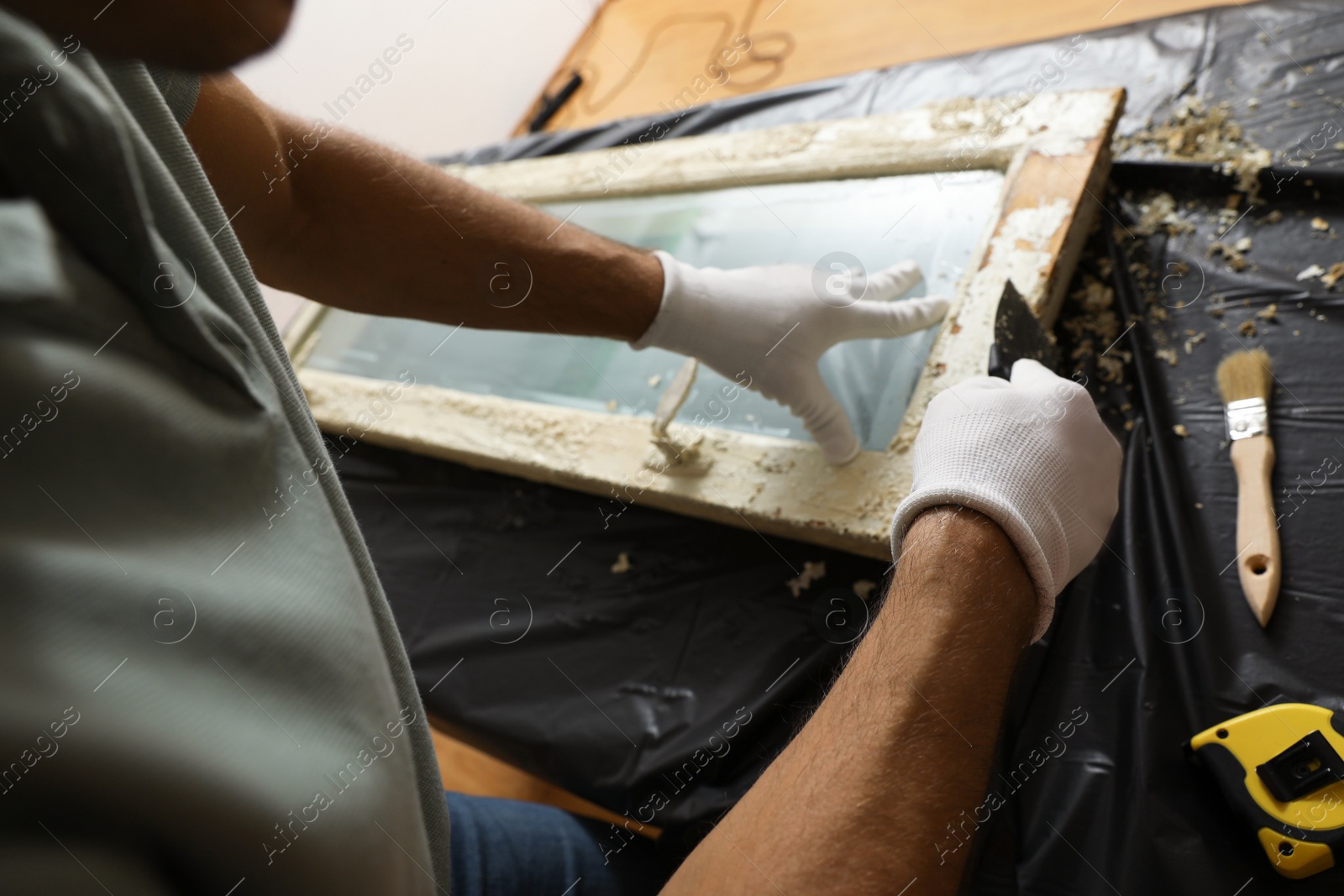 Photo of Man repairing old damaged window at table indoors, closeup