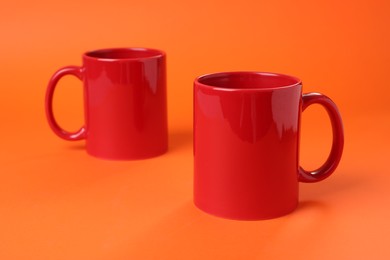 Photo of Two red ceramic mugs on orange background