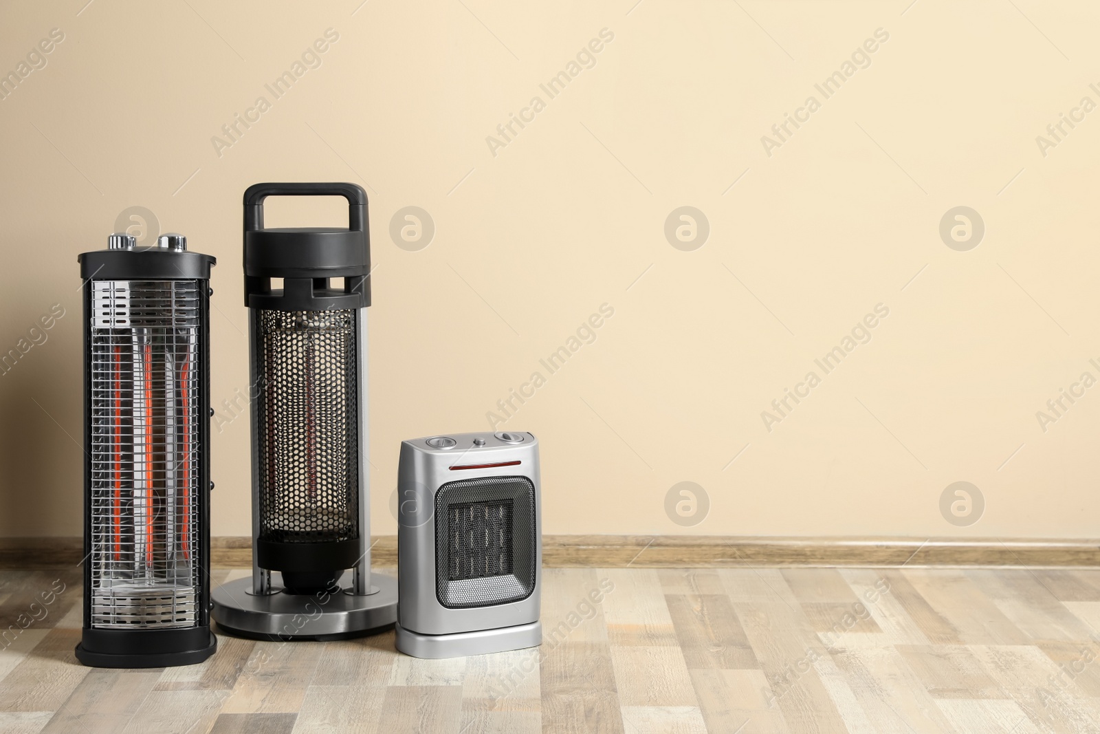 Photo of Different modern electric heaters on floor in room, space for text