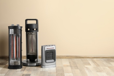 Photo of Different modern electric heaters on floor in room, space for text