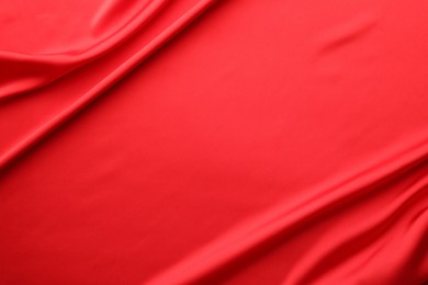 Photo of Crumpled red silk fabric as background, top view. Space for text