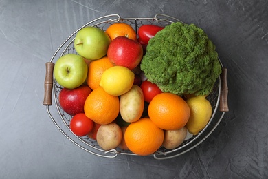 Photo of Basket with ripe fruits and vegetables on grey table, top view