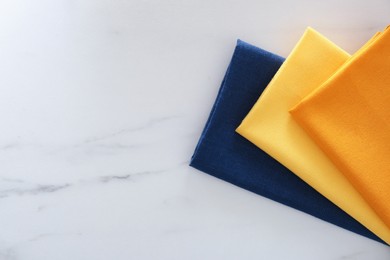 Photo of Colorful napkins on white marble table, top view. Space for text