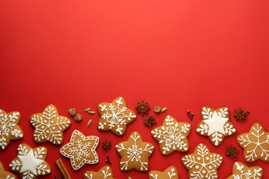 Photo of Tasty star shaped Christmas cookies with icing and spices on red background, flat lay. Space for text