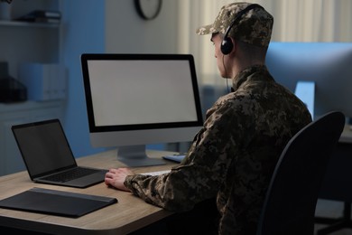 Military service. Soldier in headphones working at table in office at night